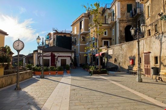 Quiet town square with clock and benches under a clear sky.