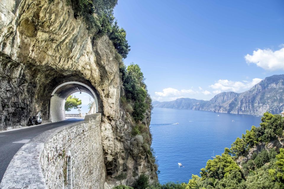 Scenic coastal road tunnel with ocean view and rocky cliffs.