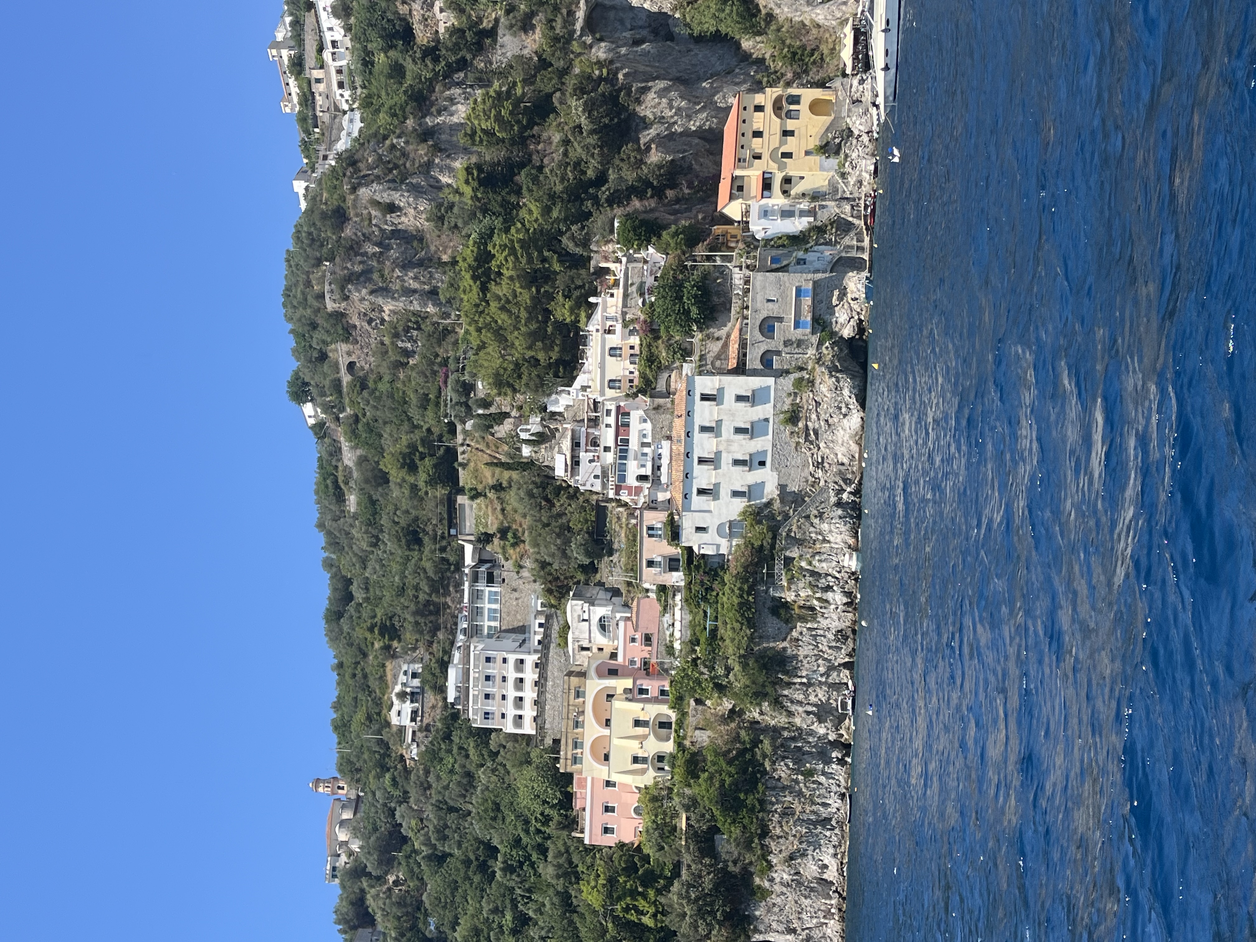 Colorful hillside buildings overlooking the sea under a bright blue sky.