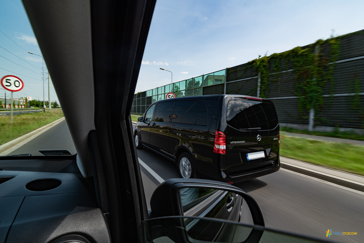 Black van driving on a road, viewed from inside another vehicle.