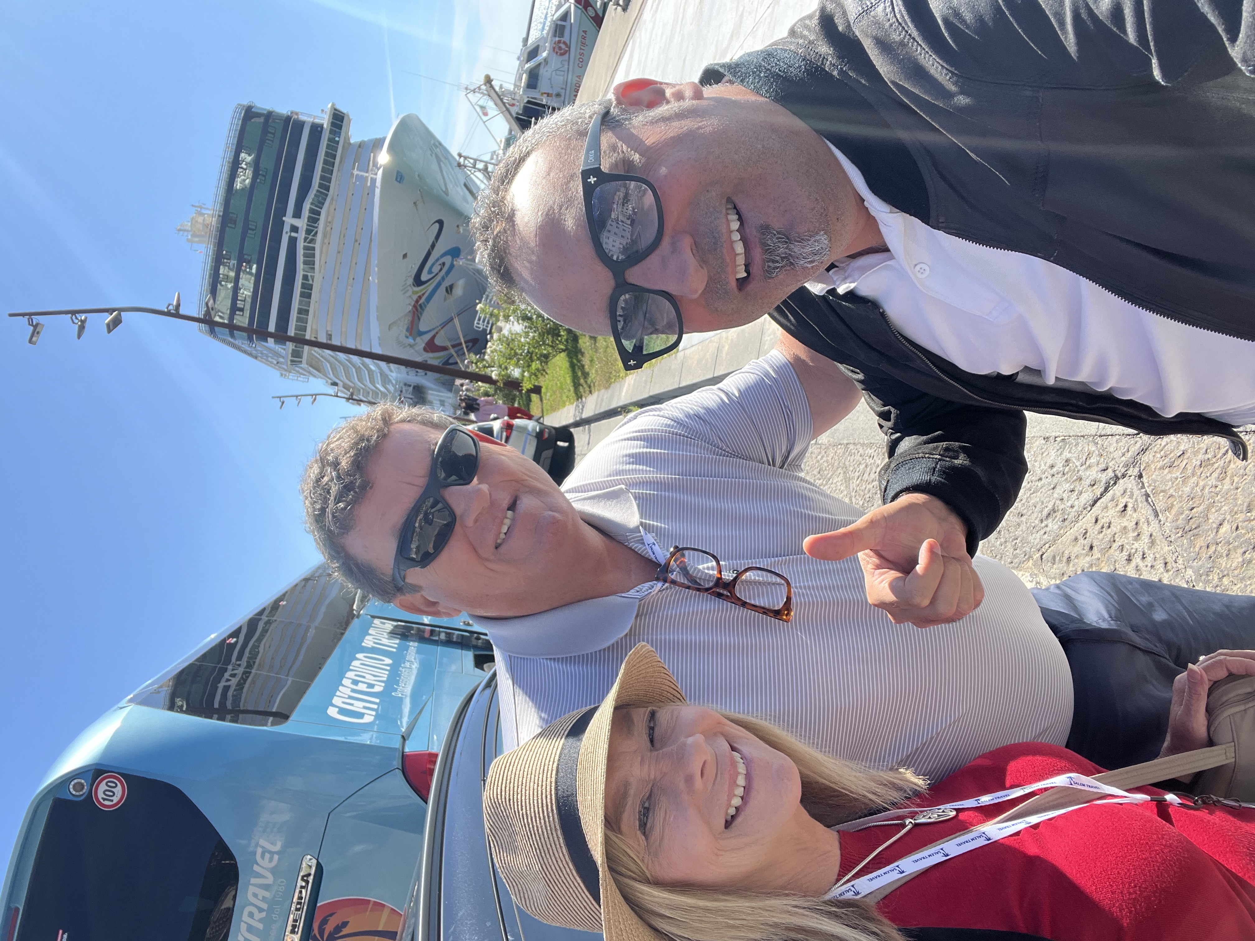 Group posing near cruise ship and tour bus.