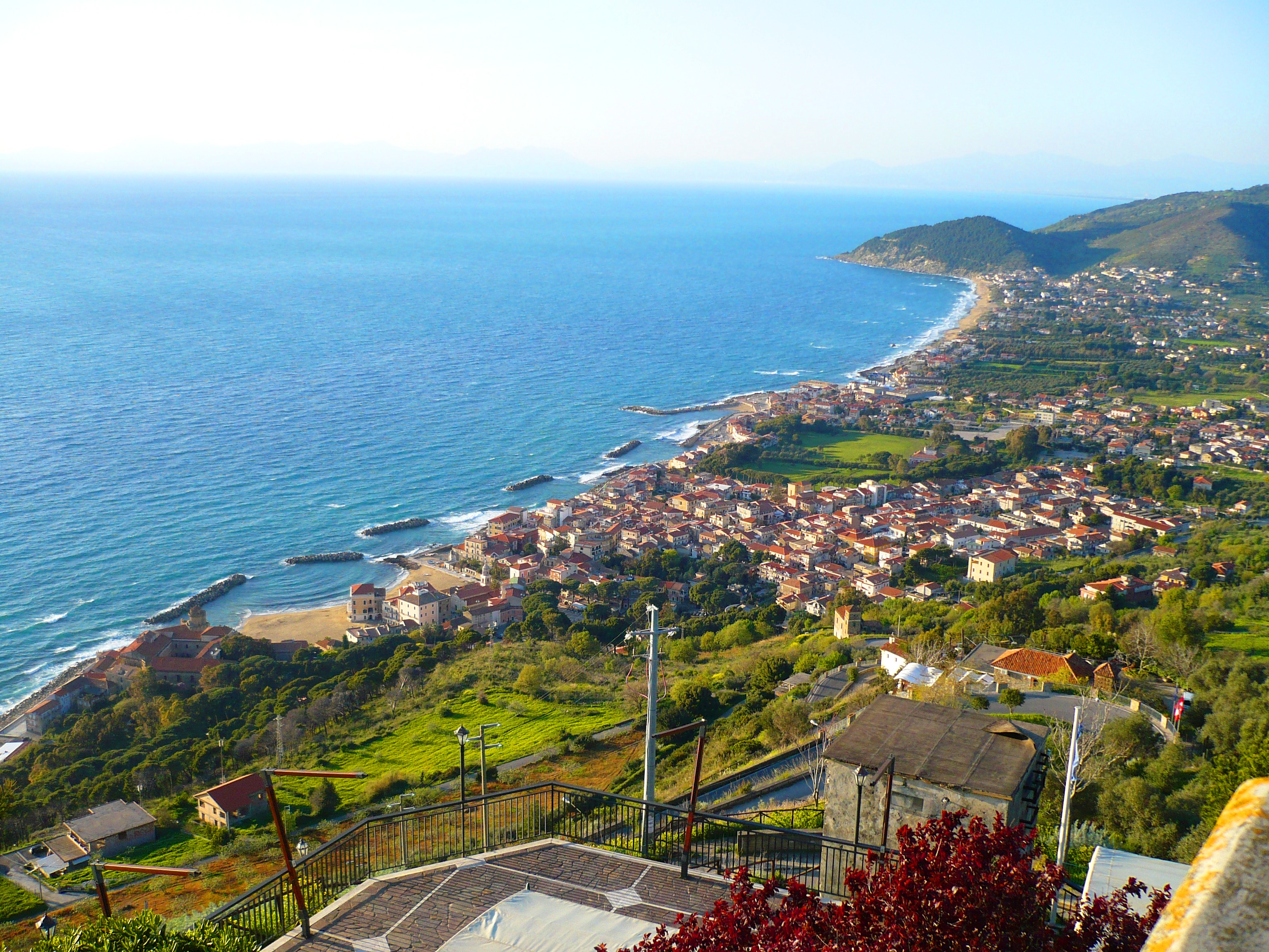 Panoramic view of a coastal town and sea from a hilltop.